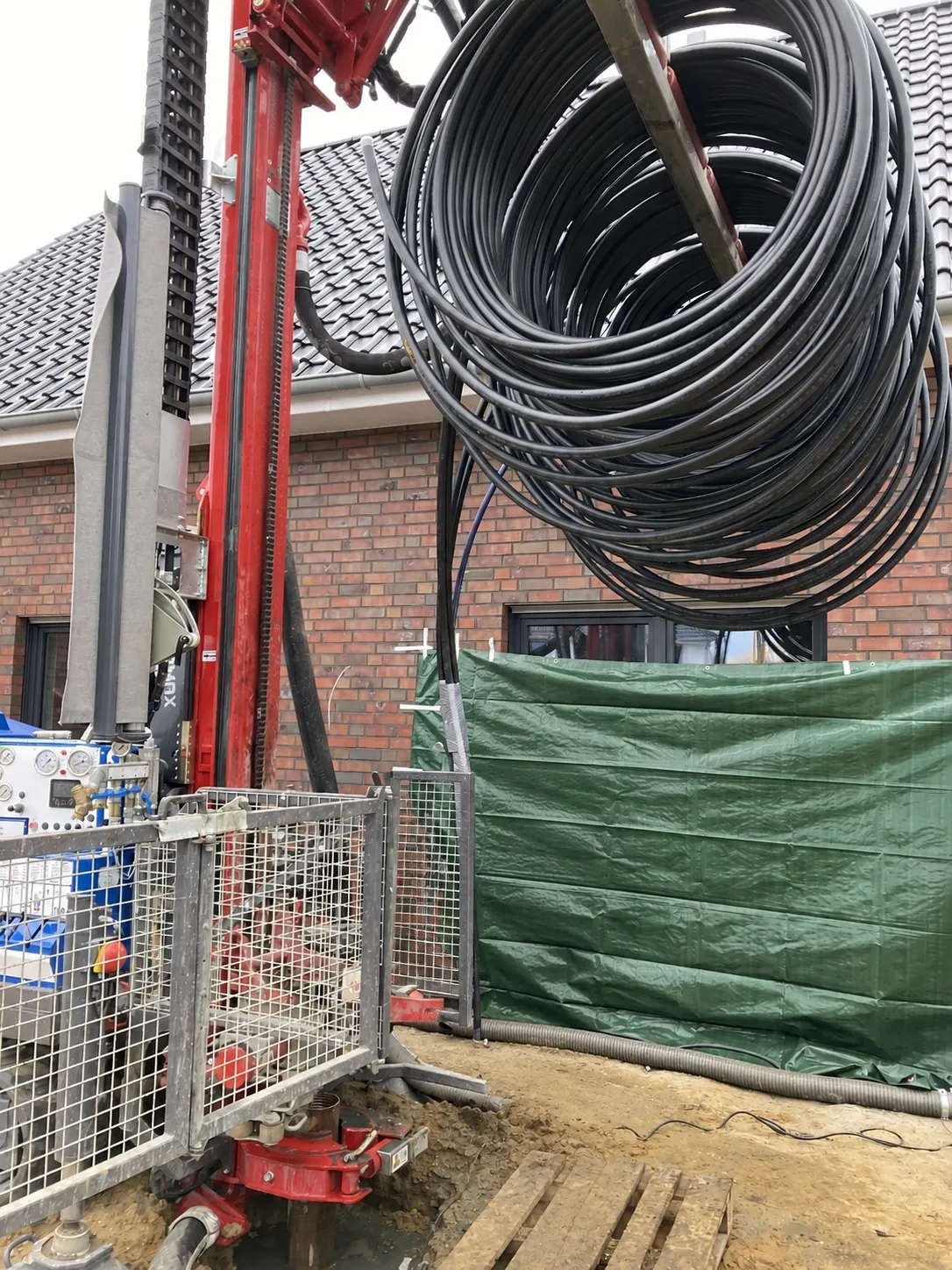 Aufgerollte Erdwärmesonde an einer Bohranlage neben einem Wohnhaus