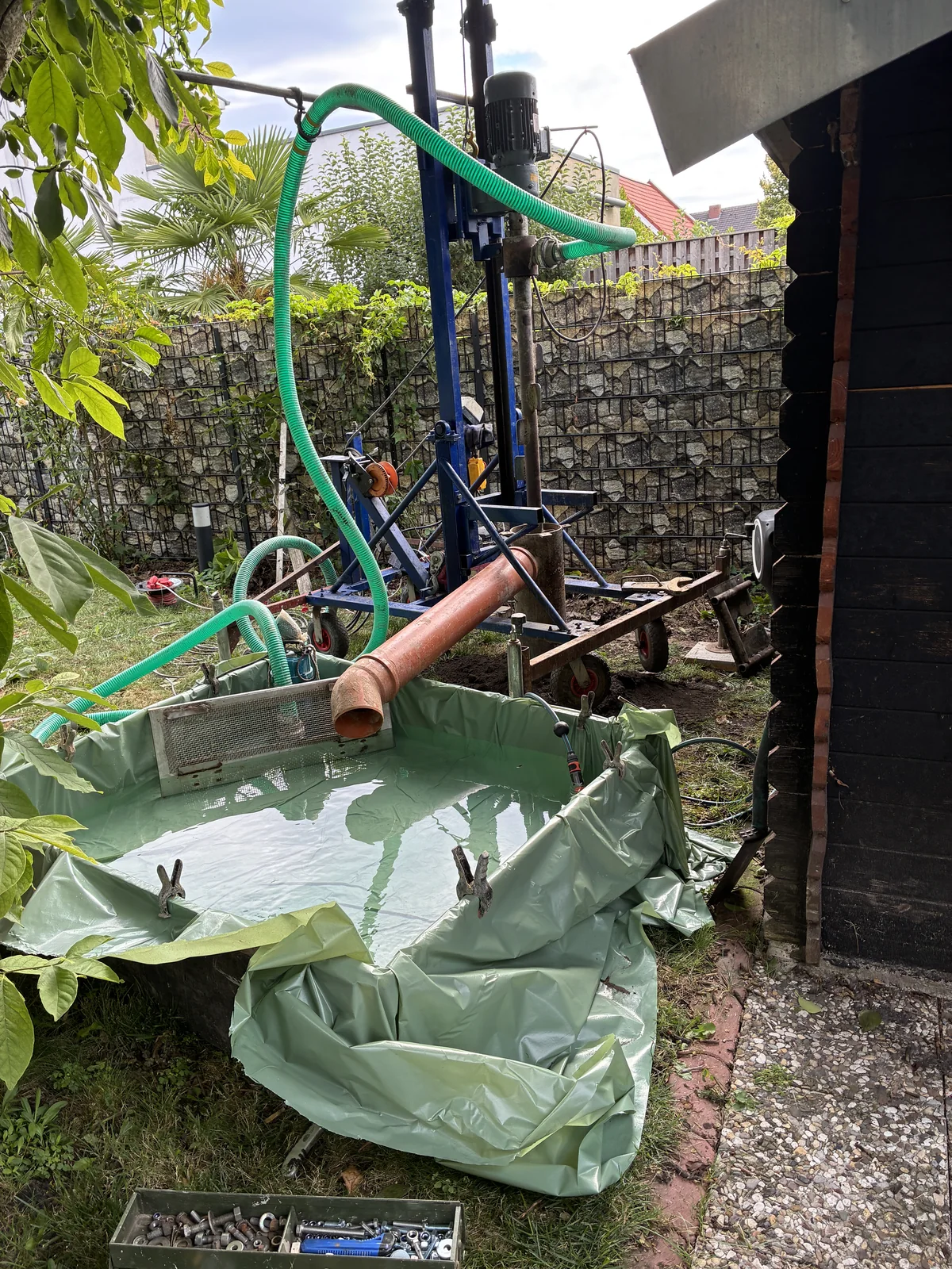 Wasserbecken und Schlauchsystem an einer Gartenbrunnenbohrung
