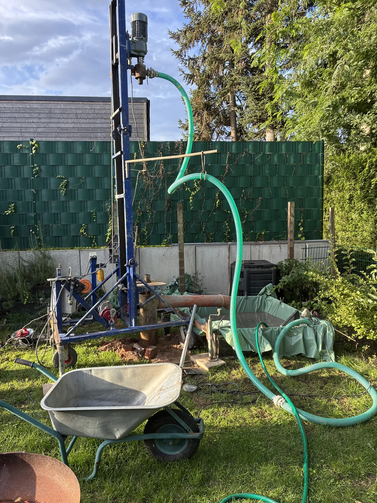 Kompakte Brunnenbohranlage neben einer Schubkarre im Garten